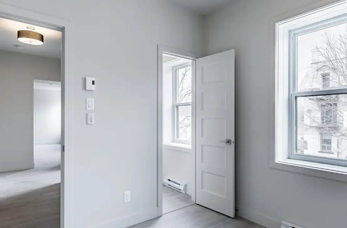 A finished room with white door casing, a panel door and window trim