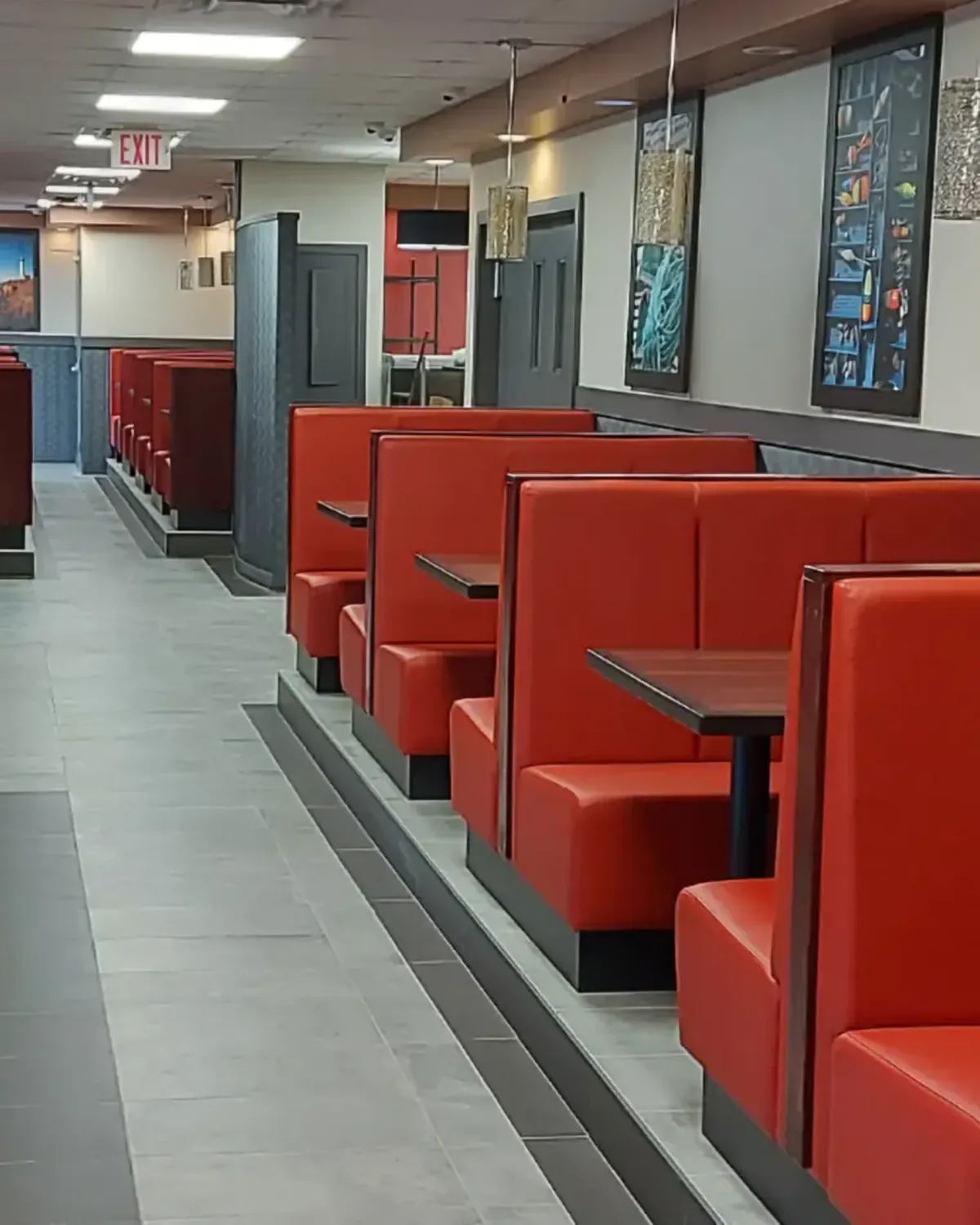 A finished restaurant dining room with red booths and framed art
