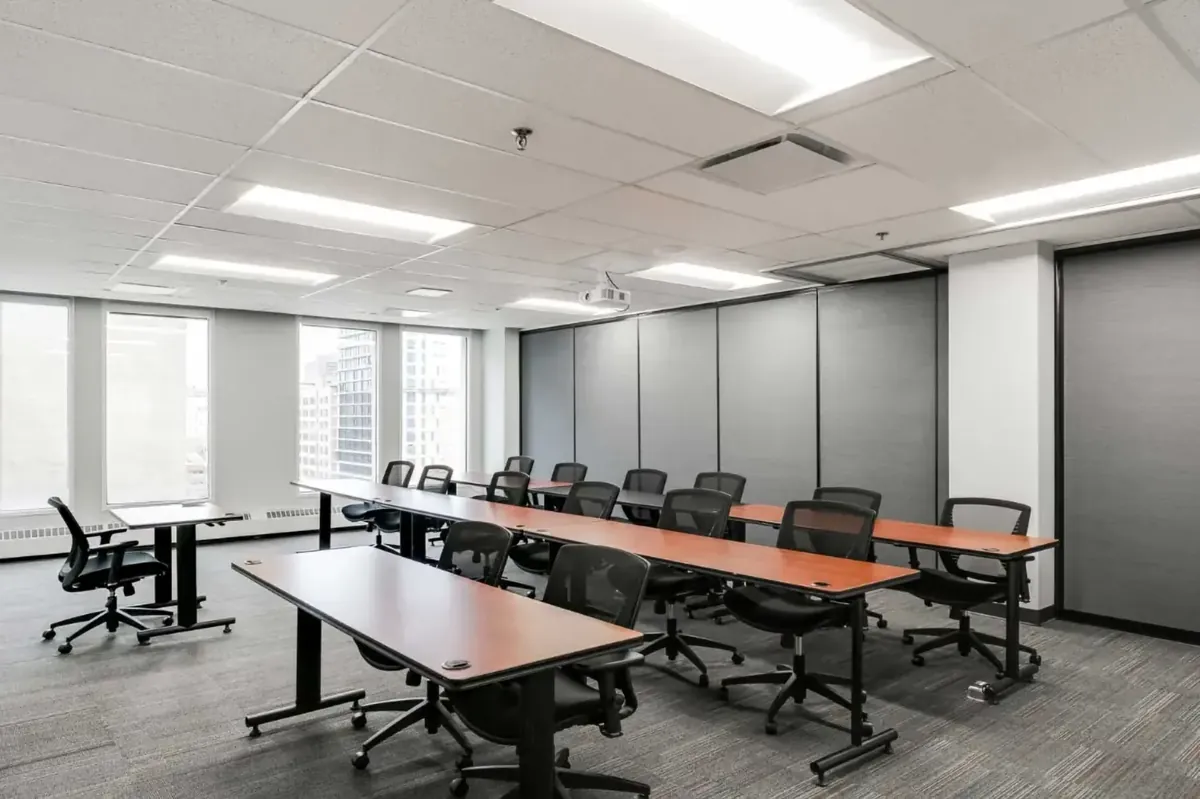 A finished training room with rows of tables, a suspended T-bar ceiling with LED panels and partition walls
